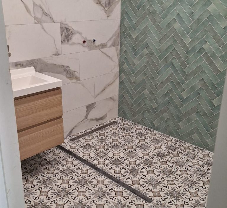Badkamer met een wastafel, groene tegelwand en een vloermotief in zwart-wit.