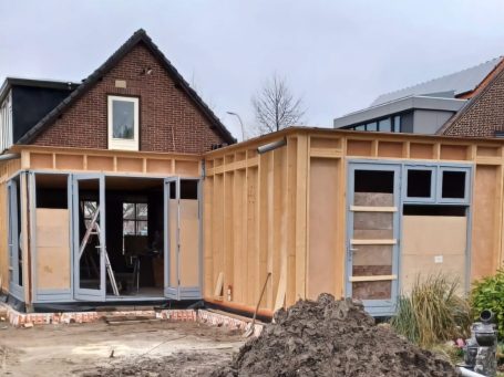 Bouw van een huis met houten buitenwanden en openstaande raamkozijnen.