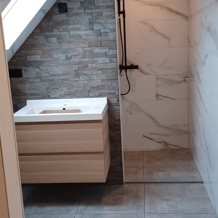 Moderne badkamer met houten wastafel en inloopdouche, lichte tegels en stenen wand.
